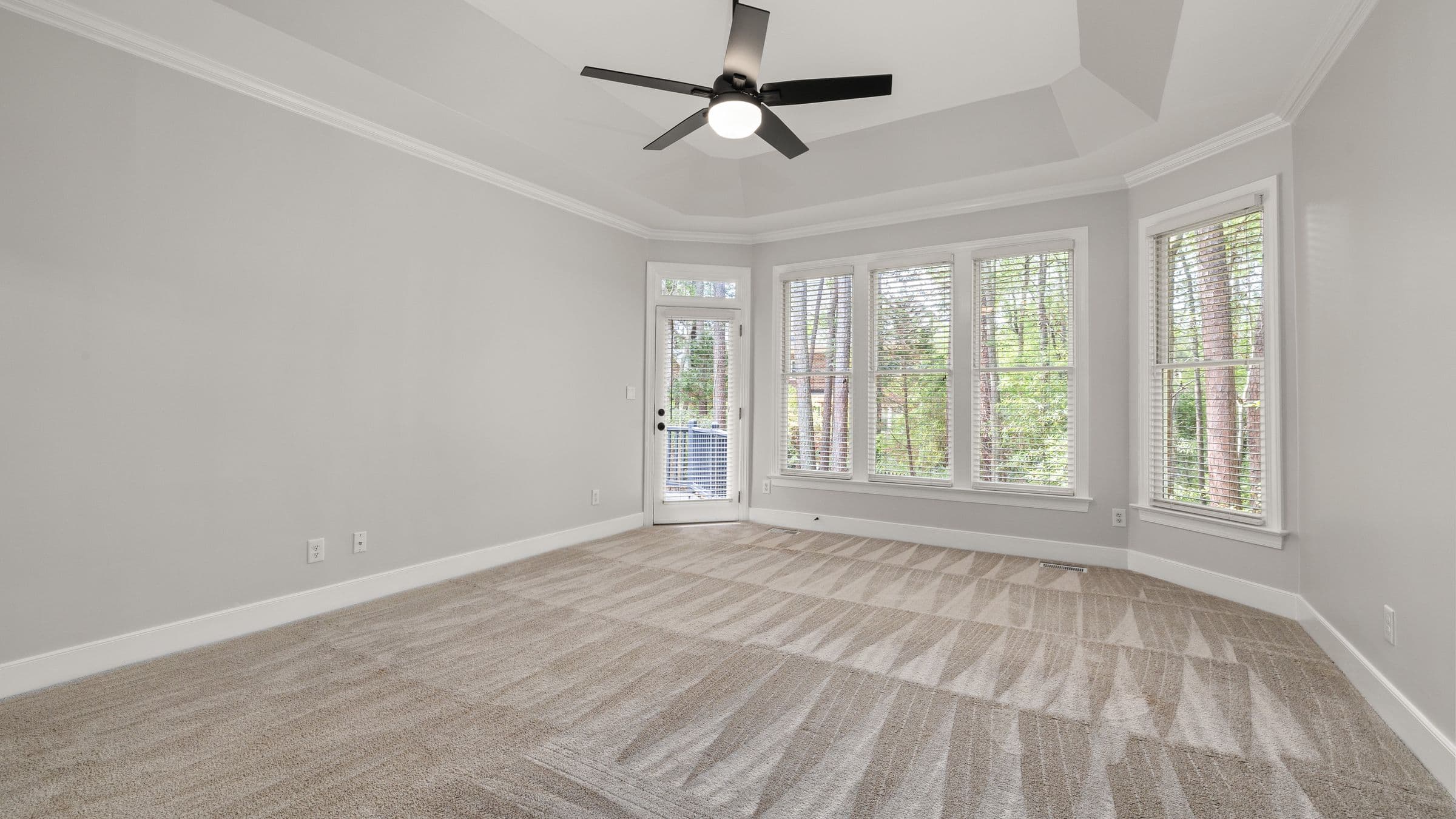 A bright empty room with freshly cleaned carpet showing vacuum lines